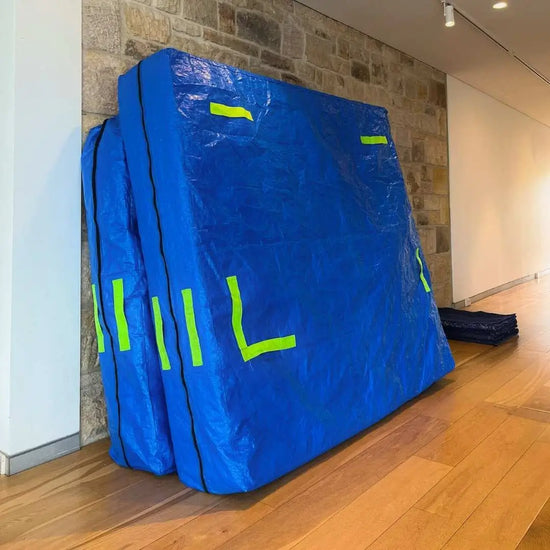 Two mattress bags standing against a wall on moving day, ready to go into storage